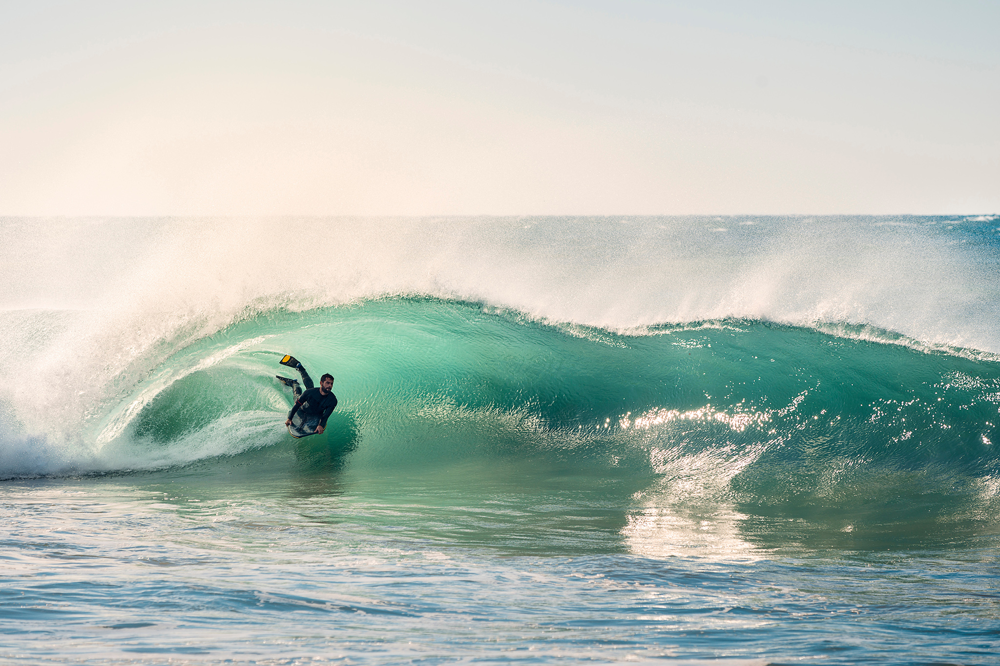 surfer riding a perfect barrel of a wave at sunset