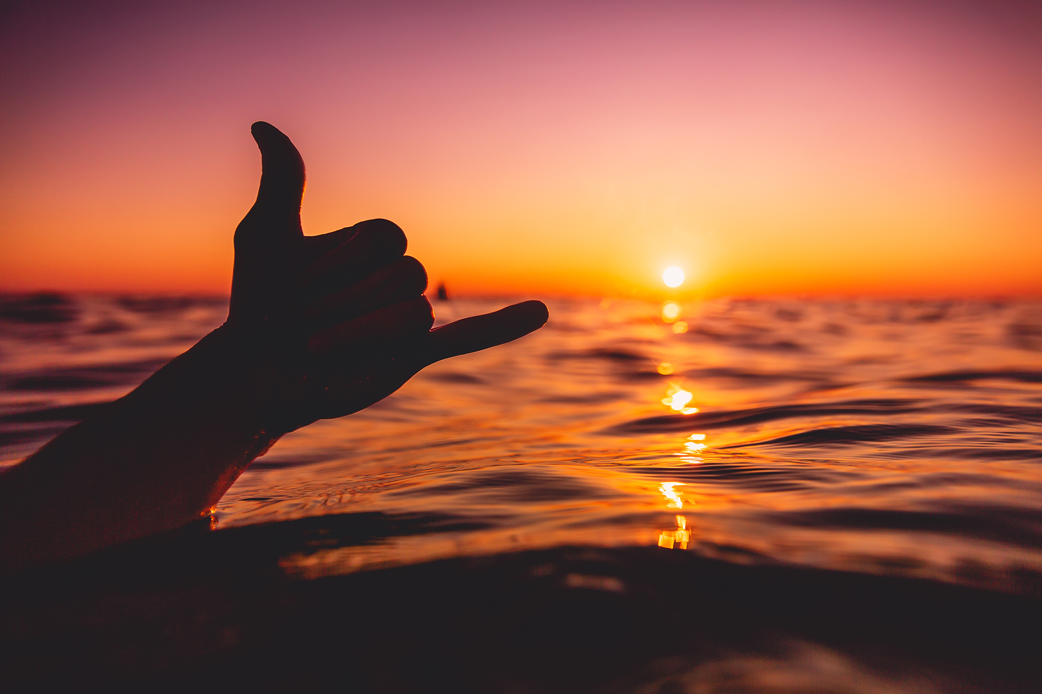 Shaka symbol and red sunset at sea. Lifestyle photo